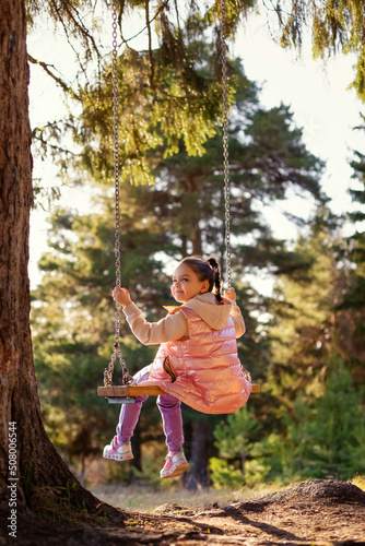 Smiling child on a swing in the park.