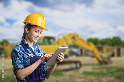 Female engineer in hard hat with tablet. Working on construction sites and buildings.