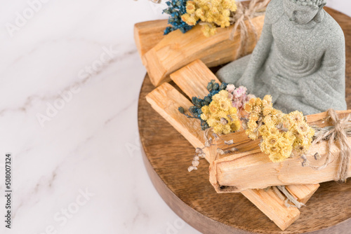 Palo santo sticks with Buddha statue in a meditation room on white marble table background with copy space. Incense for yoga, meditation and spiritual practices