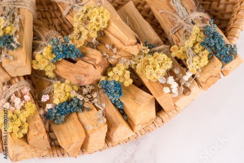 Palo santo sticks decorated with bouquets of dried flowers on natural straw tray. Holy wood sticks for meditation and spiritual practices. Esoteric ceremony and mental health concept