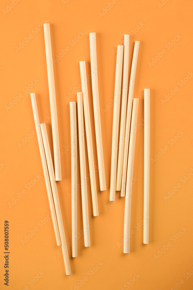 Natural wheat drinking straws made of the stem of the wheat plant on orange background. Sustainable lifestyle and zero waste concept. Ethical consumerism. Flat lay Natural wheat drinking straws made of the stem of the wheat plant on orange background. Sustainable lifestyle and zero waste concept. Ethical consumerism. Flat lay