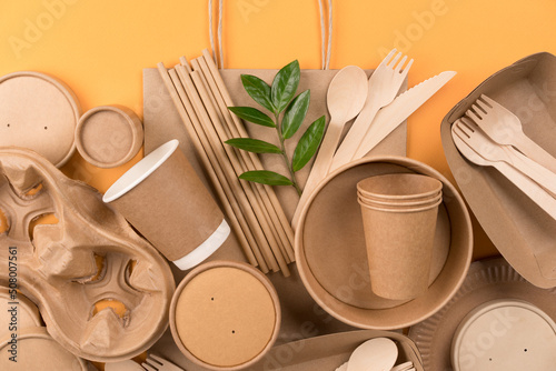 Eco-friendly paper utensils - kraft paper food packaging on orange background. Street food paper packaging, recyclable tableware, zero waste packaging concept