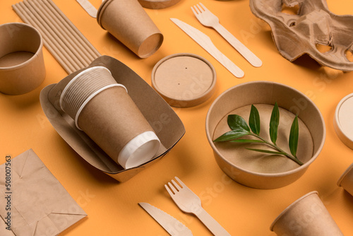 Eco-friendly paper tableware - kraft paper food packaging on orange background. Street food paper packaging, recyclable paperware, zero waste packaging concept. Flat lay, mockup image