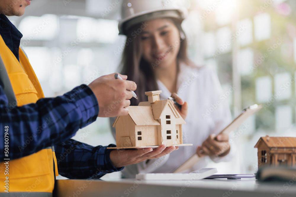Happy female architect designer in the office works with her colleagues, engineers, contractors together to design and cost housing projects. Happy female architect designer in the office works with her colleagues, engineers, contractors together to design and cost housing projects.