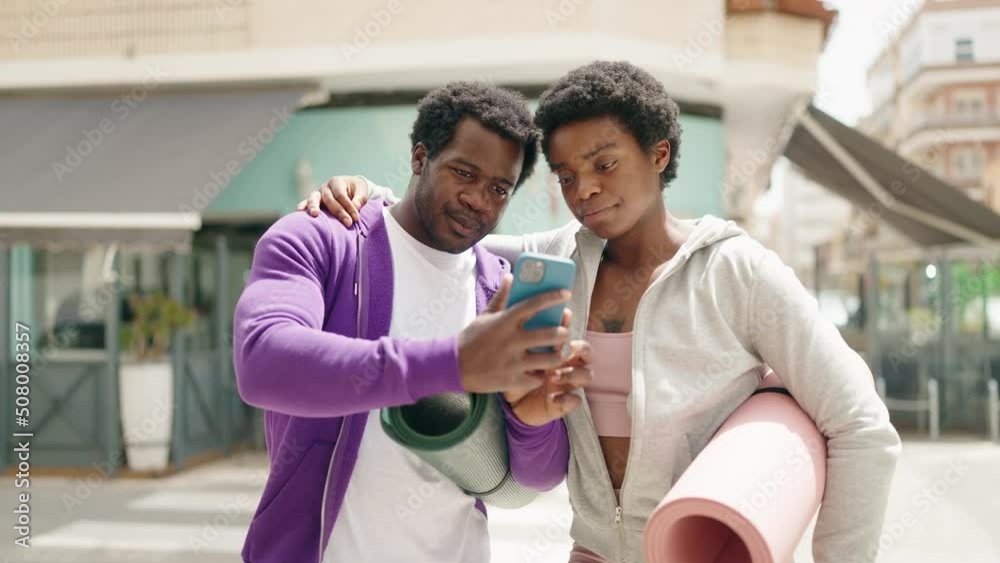 African american man and woman couple holding yoga mat making selfie by the smartphone at street African american man and woman couple holding yoga mat making selfie by the smartphone at street