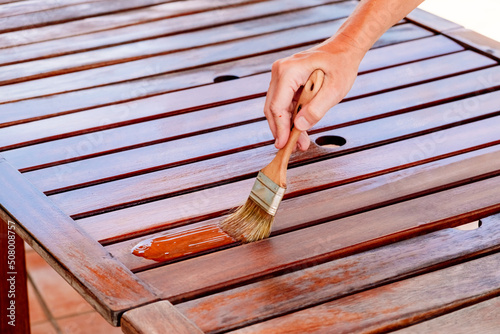 Apply teak oil on the boards of a wooden table to protect it from bad weather.