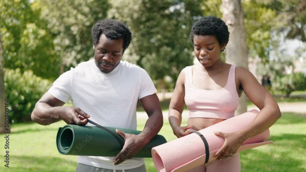 African american man and woman couple smiling confident put yoga mat on floor at park African american man and woman couple smiling confident put yoga mat on floor at park
