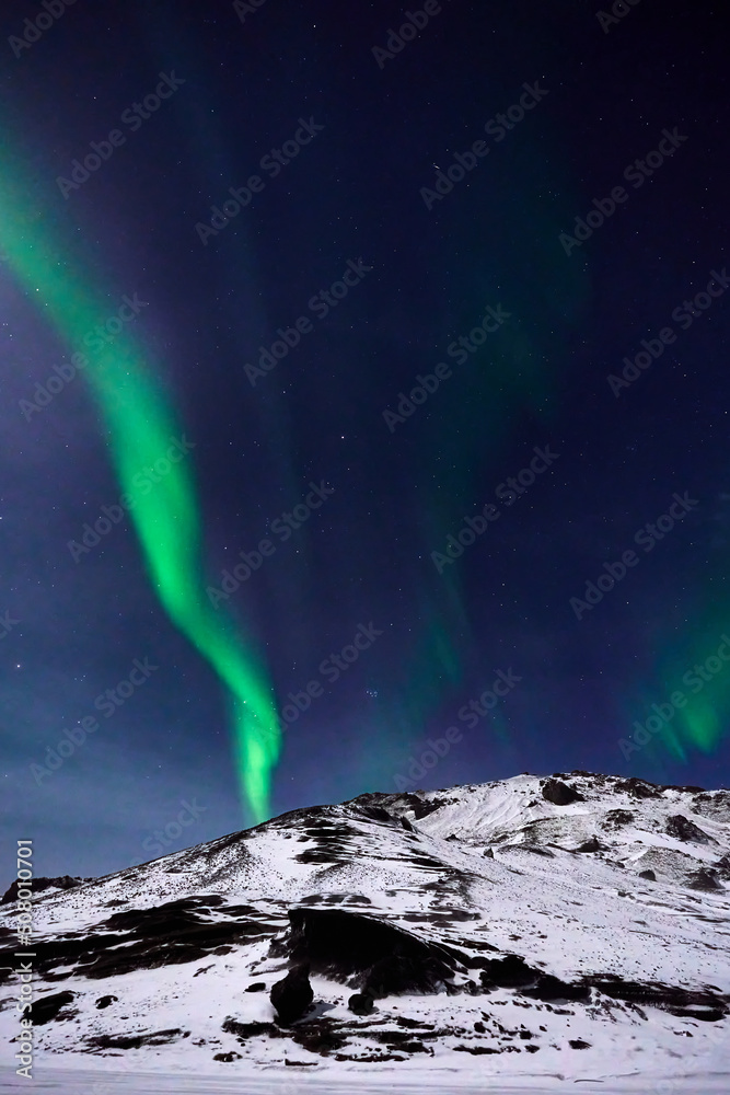 Aurora Borealis over a moonlit mountain in Iceland