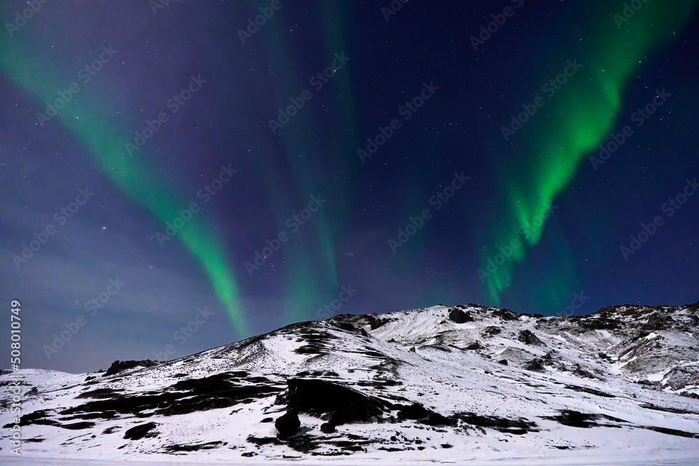 Aurora Borealis over a moonlit mountain in Iceland