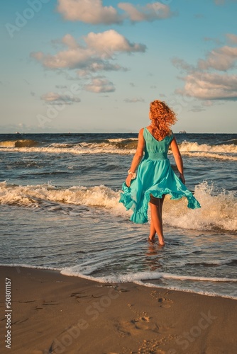 Beautiful blonde haired woman on the beach. Girl in a blue dress at the Polish seaside.