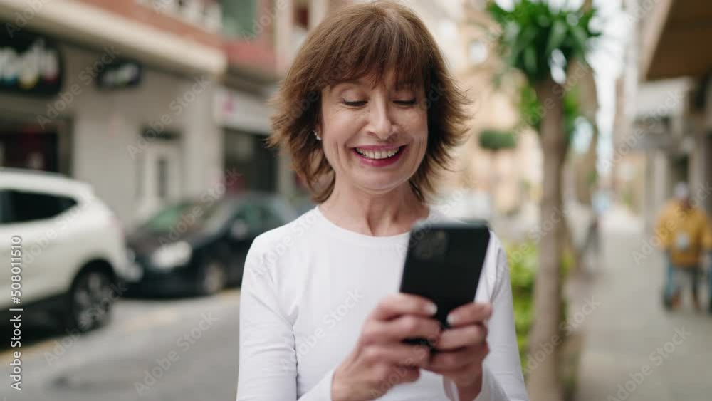 Middle age woman smiling confident using smartphone at street Middle age woman smiling confident using smartphone at street
