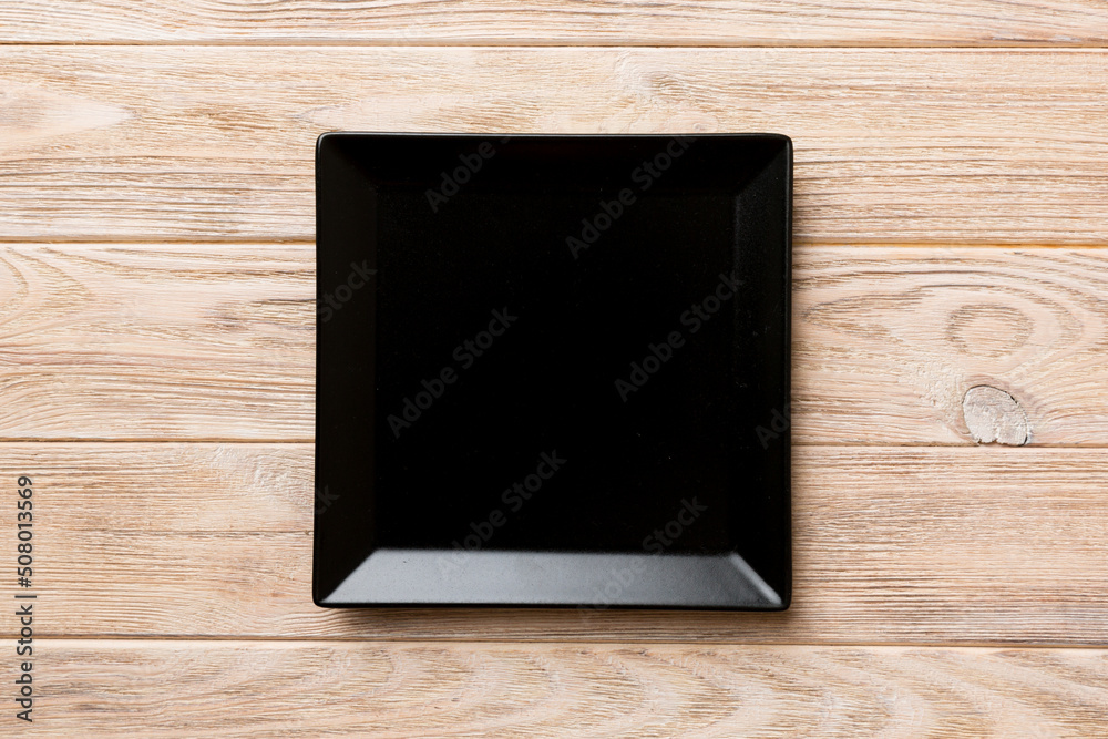 Top view of empty square plate on wooden background. Empty space for your design Top view of empty square plate on wooden background. Empty space for your design