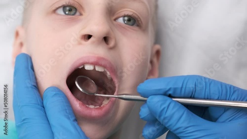 boy opens her mouth wide and pulls out long tongue. child shows his teeth soft palate and mouth to dentist. mouth is wide open, tongue is stuck out as far as possible, with clear view of tongue photo