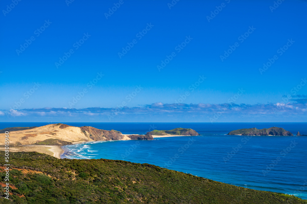 Stunning view over Te Werahi Beach and Cape Maria Van Diemen from a high vantage point in Cape Reinga. Vivid blue sea of the Tasman Sea and clear sky of a bright winter day. North Island, New Zealand Stunning view over Te Werahi Beach and Cape Maria Van Diemen from a high vantage point in Cape Reinga. Vivid blue sea of the Tasman Sea and clear sky of a bright winter day. North Island, New Zealand