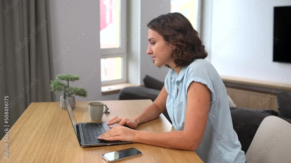 Concentrated female freelancer using laptop computer sitting at the desk in home office, response to emails, typing on the keyboard Concentrated female freelancer using laptop computer sitting at the desk in home office, response to emails, typing on the keyboard