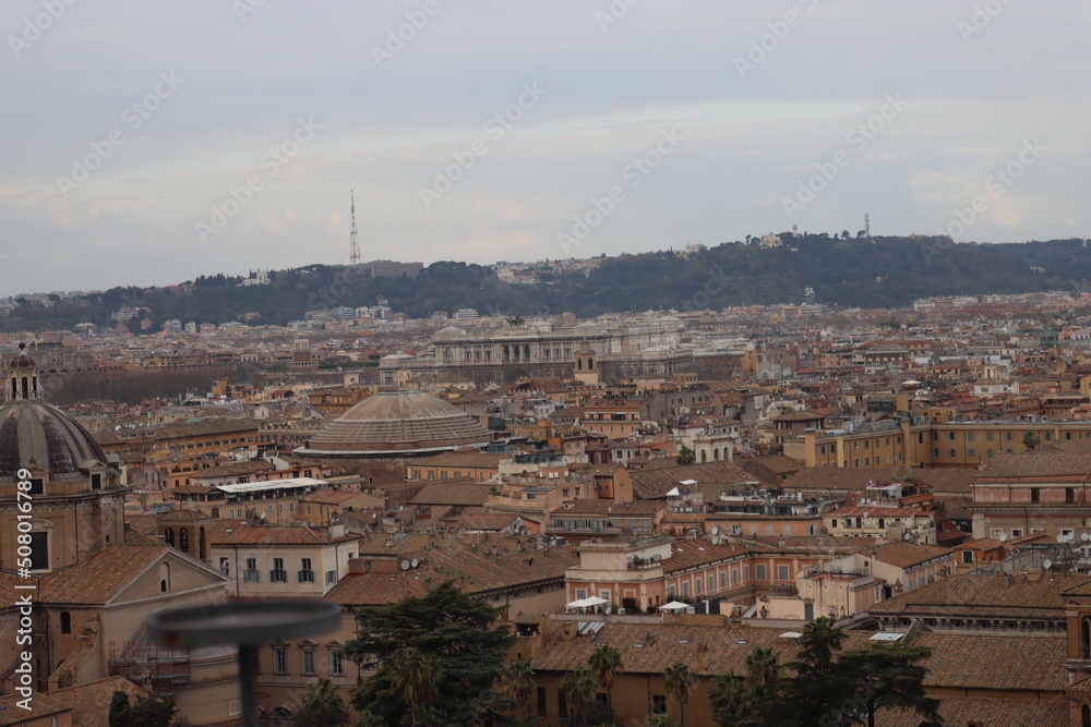 Obraz premium ROME, ITALY - February 05, 2022: Panoramic view around the Colosseum in city of Rome, Italy. Cold and gray sky in the background. Macro photography of the green parks with the old buildings.