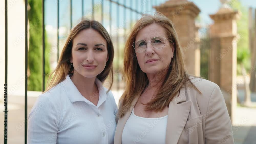 Mother and daughter standing together with serious expression at street Mother and daughter standing together with serious expression at street
