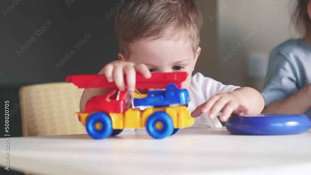 little boy and baby girl play in kindergarten. a group of children play toys indoor cubes and cars on the table in kindergarten. happy family preschool education concept. nursery baby toddler home little boy and baby girl play in kindergarten. a group of children play toys indoor cubes and cars on the table in kindergarten. happy family preschool education concept. nursery baby toddler home