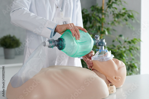 Close-up of healthcare worker using oxygen mask for respiration while practicing on dummy photo
