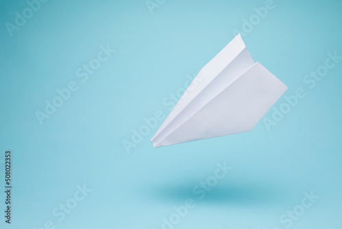 Paper plane origami isolated on blue background with copy space.