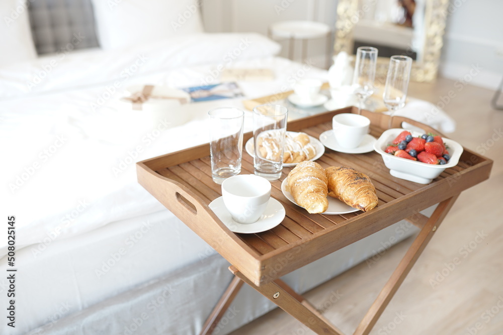 Delicious breakfast in bed. Coffee in bed on a white bed with buns, berries on a white