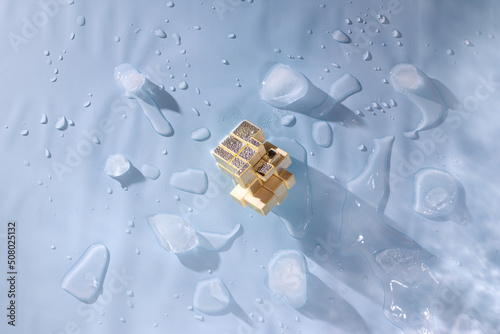 Quadro su tela Golden mirror rubik's cube, pieces of melted ice on a blue background with water drops