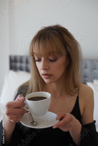 Photo of a beautiful girl in bed. Breakfast in bed. Beautiful girl having breakfast in bed
