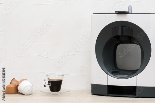 Máquina de café expresso, xícara e cápsulas exposto em uma mesa de madeira. photo
