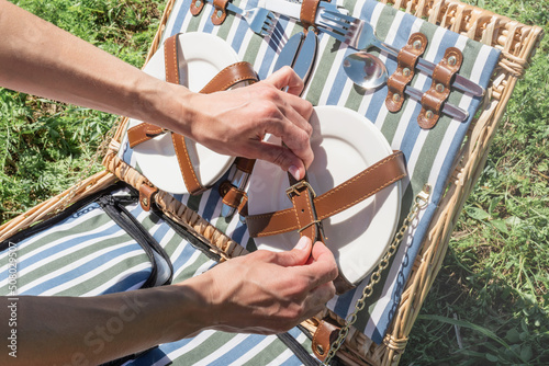 young caucasian woman hand preparing picnic basket outdoors, ready to have a picnic