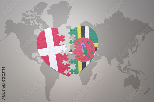 puzzle heart with the national flag of dominica and denmark on a world map background. Concept.