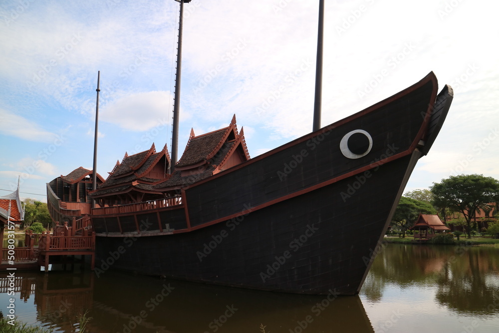 Close-up shot of a black boat docked in the harbor with three red-roofed gazebos in the middle of the boat Close-up shot of a black boat docked in the harbor with three red-roofed gazebos in the middle of the boat