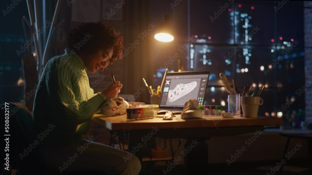 Active Female Designer Sitting at Evening in Loft Studio and Working on Shoes Customisation. Living Room with Big Window. Next Generation and Trendy Design Concept. Moving Camera Shot Active Female Designer Sitting at Evening in Loft Studio and Working on Shoes Customisation. Living Room with Big Window. Next Generation and Trendy Design Concept. Moving Camera Shot