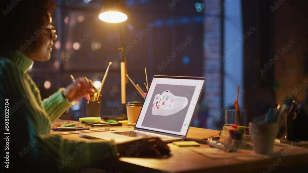 Black Teen Woman Creating and Rendering 3D Model of Unique Sneaker at Laptop Computer During Work at Evening. Freelance and Millennial People Concept Black Teen Woman Creating and Rendering 3D Model of Unique Sneaker at Laptop Computer During Work at Evening. Freelance and Millennial People Concept