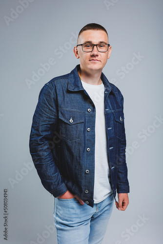 Live a rich life. Positive emotions. Portrait of a young attractive man in a white t-shirt and denim jacket. Men's clothing from the denim collection