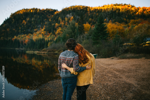 Anonymous loving couple cuddling on lake shore on autumn day photo