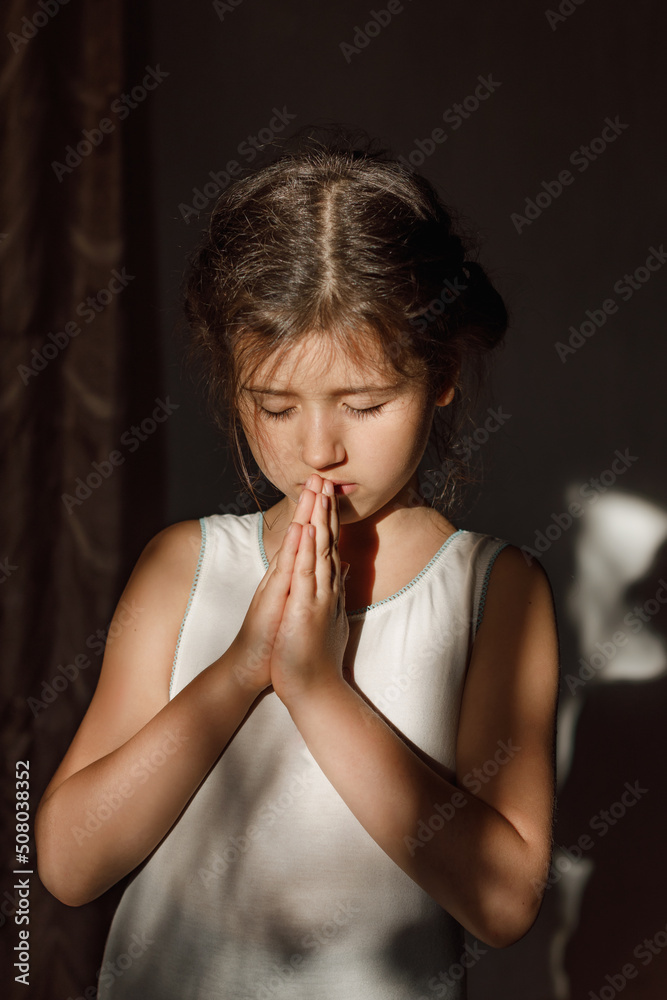 A little girl folded her hands in prayer in the hope of ending the war in Ukraine, a Ukrainian child prays and believes in a happy future A little girl folded her hands in prayer in the hope of ending the war in Ukraine, a Ukrainian child prays and believes in a happy future