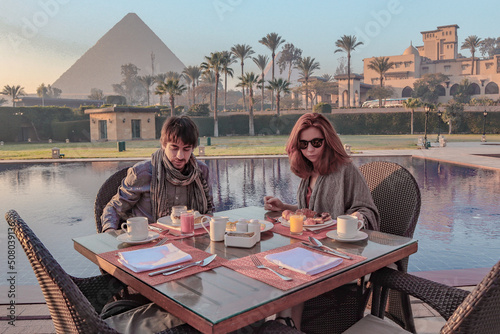 Couple enjoying breakfast with a view over the Pyramids of Giza in Caïro.