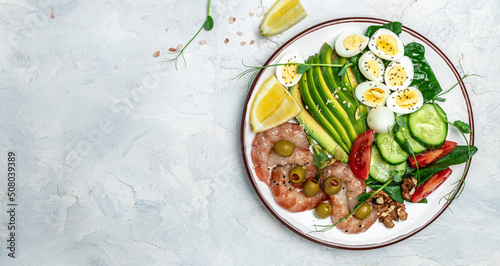 Ketogenic diet breakfast shrimps, prawns, soft fried egg, fresh salad, tomatoes, cucumbers and avocado on a light background. Keto, paleo lunch. Long banner format. top