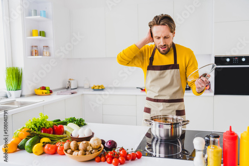 Photo of young man moody hand touch head overcooked fail prepare supper meal kitchen cuisine indoors