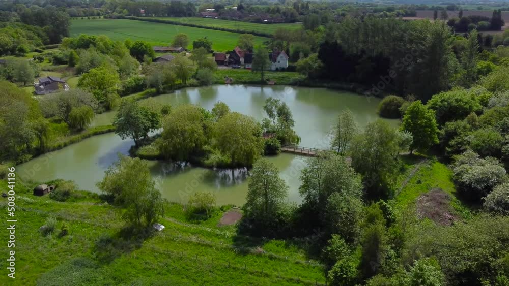 Aerial rotating shot of Weybread lake in Waveney Valley. Beautiful lakeside shot of tree surrounded the lake. Aerial rotating shot of Weybread lake in Waveney Valley. Beautiful lakeside shot of tree surrounded the lake.