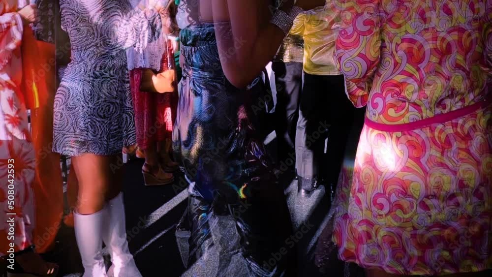 Timelapse of a crowd at a 1970s retro disco costume party. Torso tracking shot.