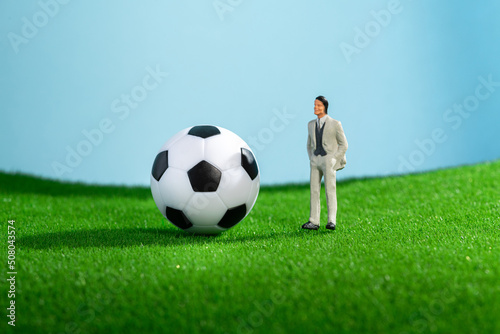 Closeup of football ball and miniature figure coach or manager model