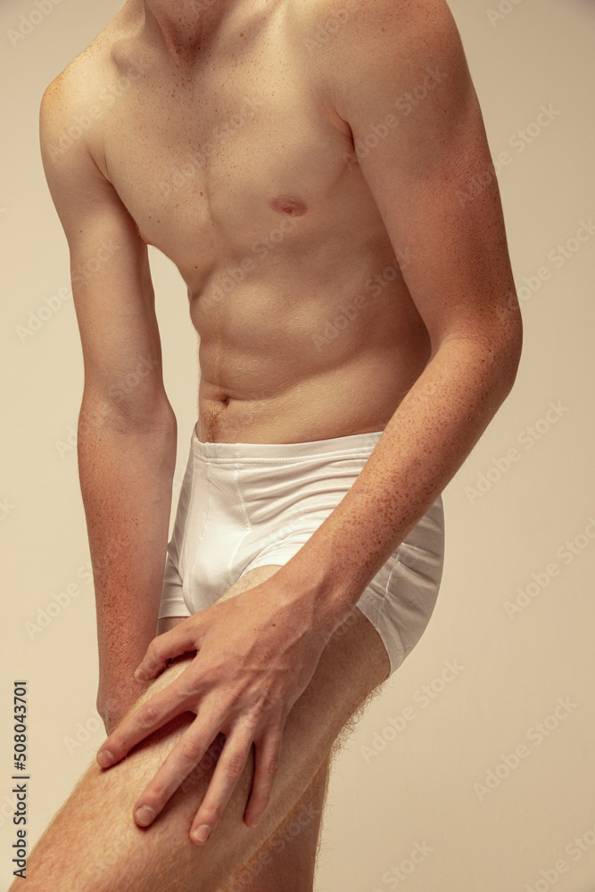 Obraz premium Cropped image of sportive male body in underwear, muscular shape, abs, hands. Model posing in underwear isolated over grey studio background