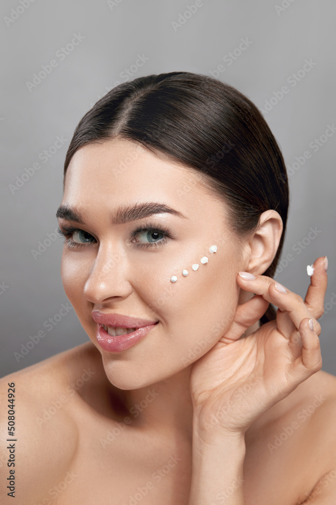 Beauty Face. Beautiful Woman With Natural Makeup Applying Cream To Her Face . Closeup Portrait Of Model Girl With Healthy Smooth Facial Skin. Beauty Face. Beautiful Woman With Natural Makeup Applying Cream To Her Face . Closeup Portrait Of Model Girl With Healthy Smooth Facial Skin.