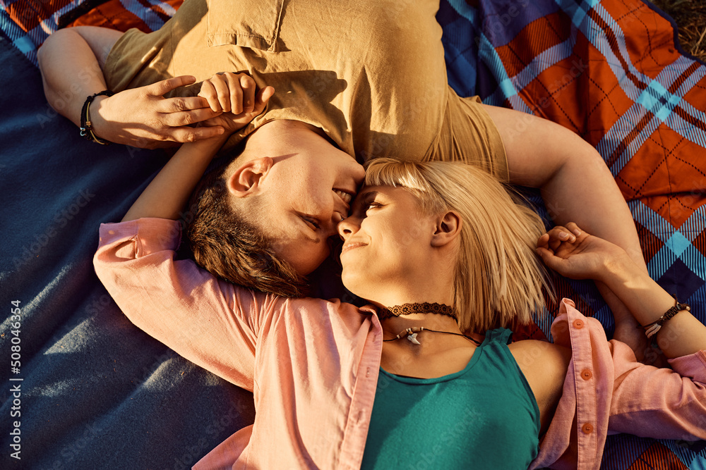 Obraz premium Above view of romantic lesbians lying down on picnic blanket.