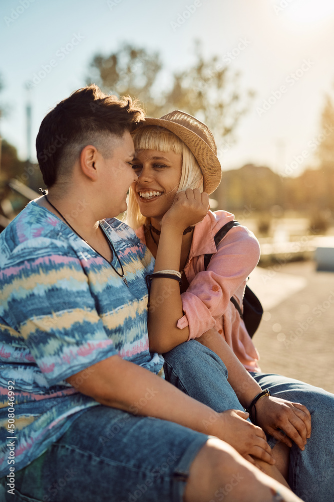 Happy female couple in love look at each other while relaxing outdoors.