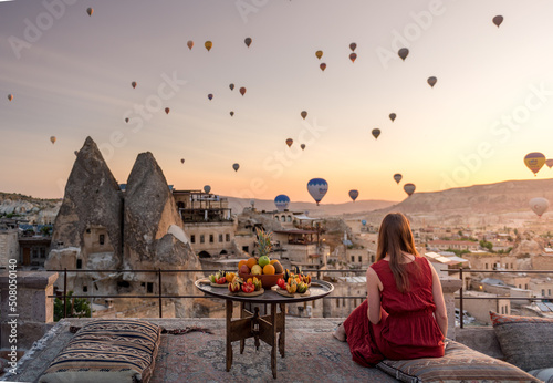 girl in red dress looking at hot air balloons over Cappadocia