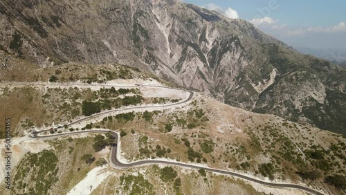 Drone circle orbit around Llogara mountain pass in Albania. Aerial view of cars driving slowly on winding road photo