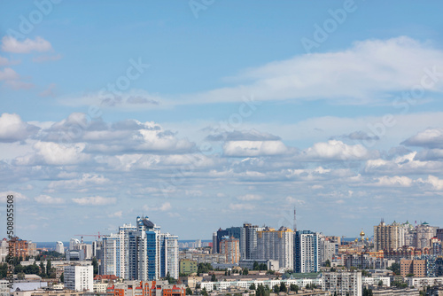 High sky with white clouds in the background of the urban landscape with new high-rise residential neighborhoods.