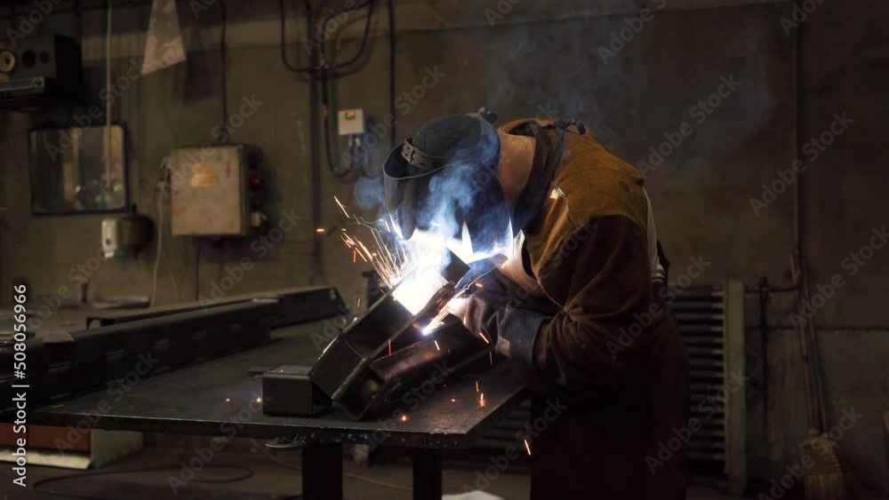 A welder in a protective mask is doing metal welding. Real time spark smoke flash. 4K Footage A welder in a protective mask is doing metal welding. Real time spark smoke flash. 4K Footage
